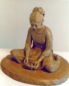 Photo of clay sculpture of a young girl holding a birds nest in her hands