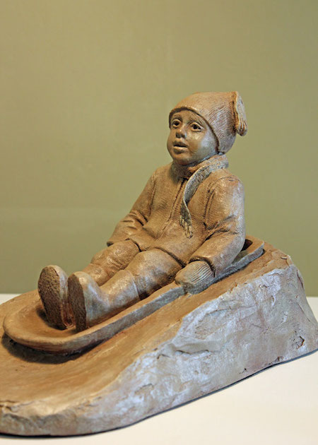 Photo of a sculpture of young child sledding in the snow