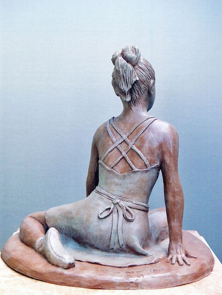 Photo of a sculpture of a young dancer sitting on the floor (back)