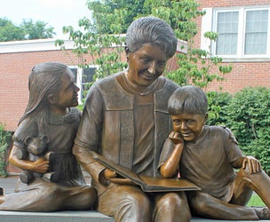 Photo of a sculpture of a woman reading a book to two children